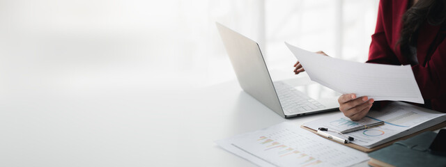 Wall Mural - A female financier is reviewing company financial documents, monthly financial statement summary from the finance department. The concept of managing the company's finances for accuracy and growth.