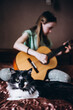 © Анна Молько - the girl is learning to play the guitar at home. learning online. a cat near a person. selective focus