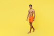 © ViDi Studio - Full body side profile view smiling young sexy man wear orange shorts swimsuit relax near hotel pool walk go look camera isolated on plain yellow background. Summer vacation sea rest sun tan concept.