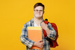 Young smiling smart man with down syndrome wear glasses casual clothes backpack look camera hold books go to school isolated on pastel plain yellow color background. Genetic disease world day concept.