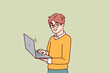 © drawlab19 - Smart little boy with open laptop for preparing homework assigned from school stands and looks at camera. Schoolboy in casual wear holding laptop using internet and learning software development