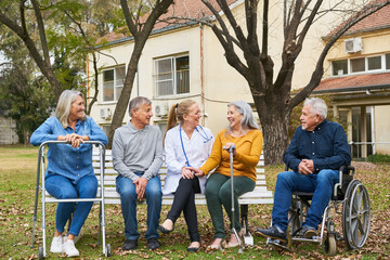 Wall Mural - Happy doctor talking to elderly people sitting in garden