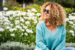 © simona - Vacation spring time season people concept lifestyle. Happy young woman smile and have outdoors leisure activity alone at the park with blossom daisy flowers in green natural background. Curly hair