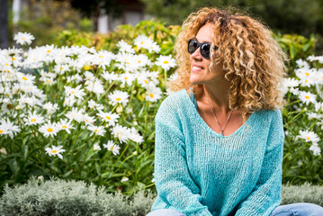 Vacation spring time season people concept lifestyle. Happy young woman smile and have outdoors leisure activity alone at the park with blossom daisy flowers in green natural background. Curly hair