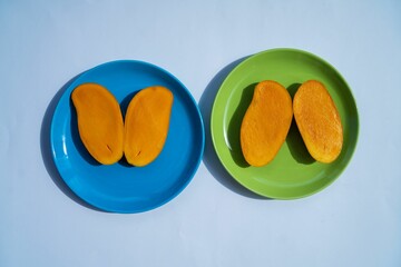 Poster - Top view of the tasty ripe mango slices on the blue and green plates