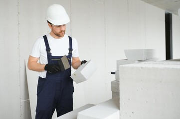 Wall Mural - Portrait of positive, handsome young male builder in hard hat.