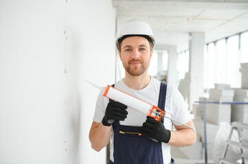 Wall Mural - Professional Workman Applying Silicone Sealant With Caulking Gun on the Wall