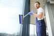 © Serhii - An employee of a professional cleaning service washes the glass of the windows of the building. Showcase cleaning for shops and businesses.