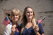 This image shows a mother and daughter posing together while holding American flags.