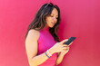 © ADDICTIVE STOCK - Woman using smartphone near pink wall