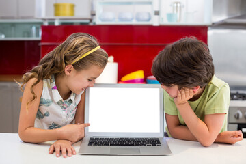 Wall Mural - Smiling siblings looking at laptop