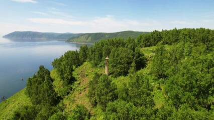 Wall Mural - Flying over the trees past the old lighthouse to the shore of the lake near the village of Port Baikal.