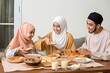 © nataliya_ua - group of happy  muslim having dinner  during ramadan celebration,family cooking together, ai generative