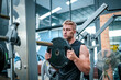 © FotoArtist - Male athlete exercising in the gym, lifting weights, pulling joints.