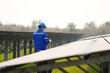 © FotoArtist - Electrician engineer with white helmet working at a photovoltaic farm, checking and maintenance equipment with instruments at industry solar power.