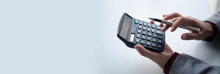 Close up view of  Businessman using a calculator to calculate financial accounts at his office desk.