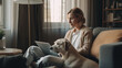 © nenetus - Confident mature woman accompanied by her dog working with laptop while sitting on couch at home.