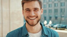 Portrait Of Handsome Smiling Stylish Hipster Lumbersexual Model. Man Dressed In Jeans Jacket Clothes. Fashion Male Posing On The Street Background
