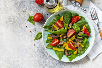 Wall Mural - Warm salad of young spinach, chicken liver, tomatoes and grilled peppers with spices and balsamic. Healthy keto diet low carb. View from above. Copy space.