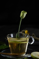 Wall Mural - Vertical shot of a cup of spiced tea with a beautiful rose bud and a slice of apple