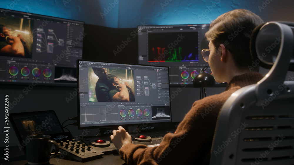 The editor works in studio on computer, uses color grading control ...