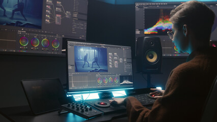 Female editor uses color grading control panel, edits video, makes movie color correction on computer and tablet in studio. Film footage and RGB wheels on monitor. Big screens with program interface.