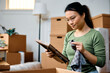 © Drazen - Young Asian woman cleans photo frame while unpacking her belongings and moving in new home.