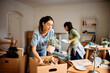 Young woman and her friend packing their belongings while preparing to move out of apartment.
