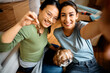 © Drazen - Happy female friends take selfie while moving into new home.