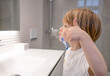 © Danko - Little blond boy learning brushing his teeth in domestic bath. Kid learning how to stay healthy. Health care concept.