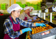 © JackF - Portrait of positive woman with peaches in her hands next to the fruit sorting line