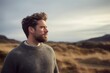 © Robert MEYNER - Medium shot portrait photography of a tender man in his 30s wearing a cozy sweater against a windswept or dramatic landscape background. Generative AI