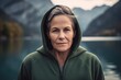 © Robert MEYNER - Portrait of a senior woman wearing a hoodie standing by a lake