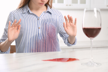 Sticker - Woman with wine stain on her shirt at white marble table indoors, closeup