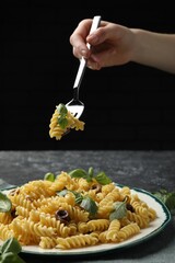 Wall Mural - Woman eating delicious pasta with anchovies and basil at table, closeup