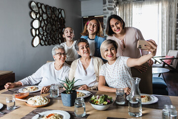 Wall Mural - latin Multi Generation women Family Posing For photo Selfie at dinner time At Home Together in Latin America