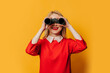 © Masson - Stylish blonde hair woman in red dress with binoculars on yellow background