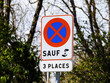 A warning sign with clear text and a tree in the background stands alone on an empty road, providing guidance to drivers during the day parking allowed only for three cars - French sign