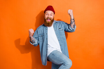 Wall Mural - Photo of young funky guy red beard yelling celebrate victory his football club fan fists up wear denim shirt isolated on orange color background