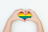 Fototapeta Tęcza - Heart with LGBT flag in female hands on white background