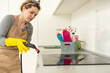 © Angelov - house cleaning. Girl brushes steam cleaners kitchen white electronic parable steam in gloves. cleaning of a surface. light kitchen.