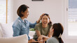 © ChayTee - Middle aged mom smile look at two grown up kid child relax hug cuddle stroking with love care warm time. Asia people woman adult older mum parent sitting at home sofa sweet trust moment happy life.