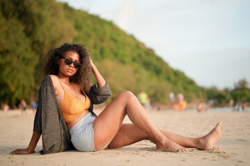 Wall Mural - African woman sit on the beach. Portrait sexy African lady travel ping and relaxing in the summer with tropical nature.