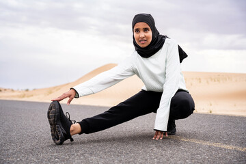 Wall Mural - Beautiful middle-eastern arab woman wearing hijab training outdoors in a desert area - Sportive athletic muslim adult female wearing burkini sportswear doing fitness workout