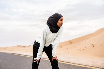 Wall Mural - Beautiful middle-eastern arab woman wearing hijab training outdoors in a desert area - Sportive athletic muslim adult female wearing burkini sportswear doing fitness workout