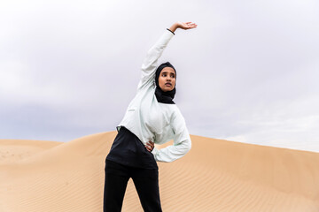 Wall Mural - Beautiful middle-eastern arab woman wearing hijab training outdoors in a desert area - Sportive athletic muslim adult female wearing burkini sportswear doing fitness workout