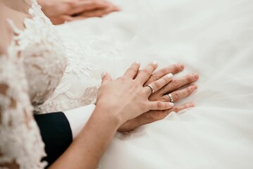 Wall Mural - Hands of the groom and bridge with rings on the white wedding dress
