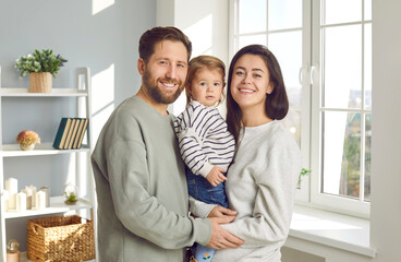 portrait of young man and wife holding their cute little daughter in their arms together. happy cauc