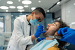 © Dorde - Young confident female dentist dedicated dental specialist removing dental plaque working on dental filling examining patient's teeth during appointment at modern dental clinic.