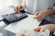 © rogerphoto - Woman accountant using a calculator and laptop computer while counting taxes for a client. Business audit and finance concepts